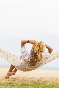 坐在沙滩吊床上的女人。 旅行和度假的概念。
