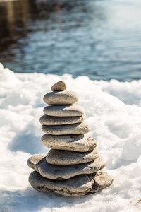 从靠近大海的白雪上以金字塔形式出现的石头形成的概念