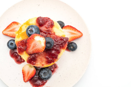 薄煎饼与草莓蓝莓和浆果酱分离白色背景