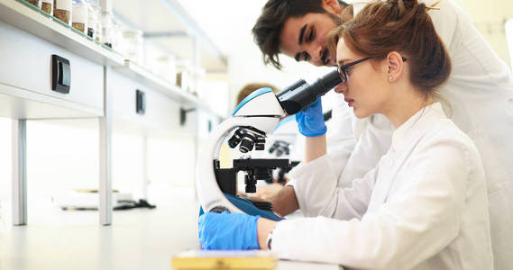 年轻的女科学家在实验室里看显微镜