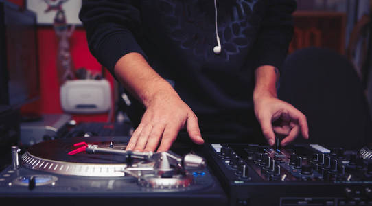 DJ在嘻哈音乐晚会上播放音乐。可用的乙烯基录制播放器和唱片播放机的声音技术，用于唱片骑师抓取乙烯基唱片和混合曲目