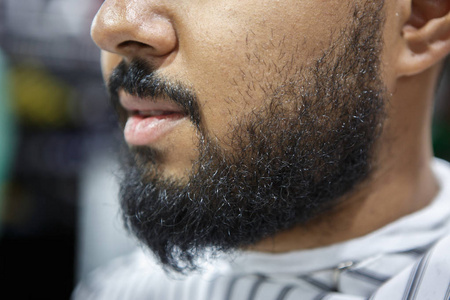 理发店年轻黑人的胡子。顾客在等理发师修剪他的胡子。 男性美容护理理念