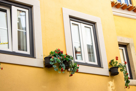 黄色的墙，有窗户和花箱。 欧洲建筑葡萄牙。 门面装饰。 外观设计。 暑期旅游概念。 房子装修。