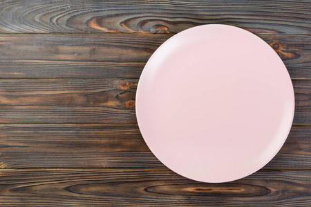 上面的空粉红色哑光盘晚餐在深色木制背景和复制空间。
