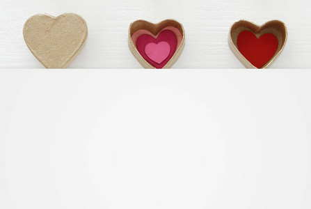 s day concept. hearts as paper gift boxes over wooden white back