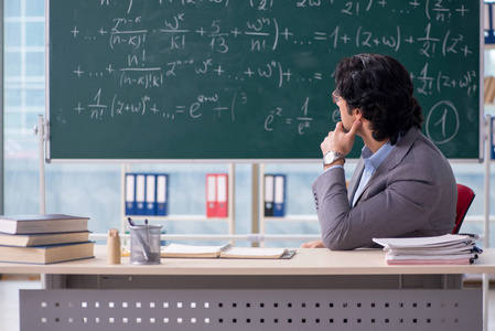 年轻的英俊数学老师在教室里摄影图