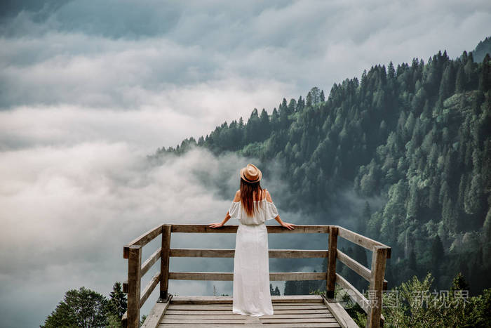 那个头戴帽子,穿着白色衣服的女人, 站在大自然中的山上照片-正版商用