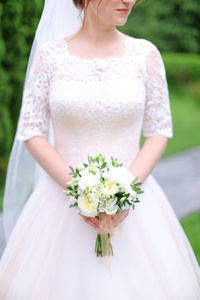 高亚新娘保留花束花束, 并穿着白色礼服与面纱
