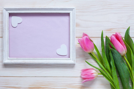 一束粉红色的郁金香，放在木制的白色框架里，用于文字。俯视图，特写，平躺在白色木制背景上