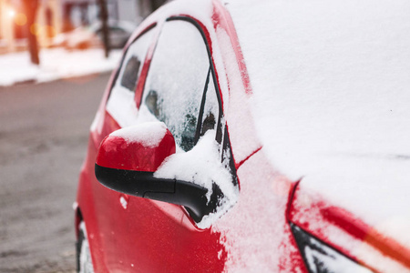 白雪覆盖着红色的汽车。停车车辆关闭。这台机器上覆盖着海霜。冬季降雪。