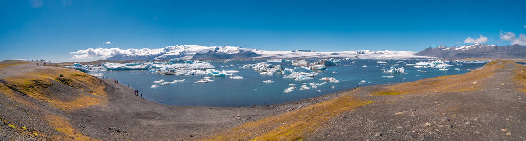 冰岛Jokulsarlon冰川泻湖与冰山和徒步旅行者的全景