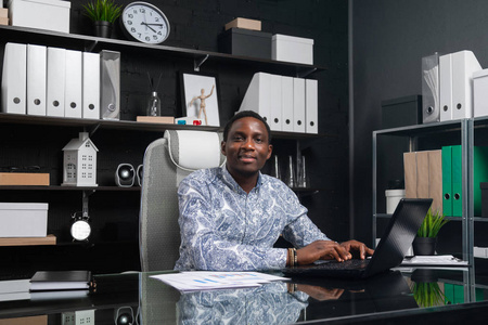 美丽的年轻非洲裔美国商人的肖像与文件和笔记本电脑在办公室工作照片