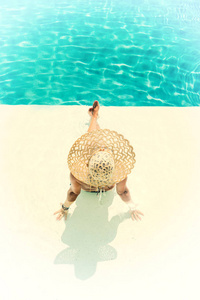 戴帽子的漂亮女人在度假村享受游泳池