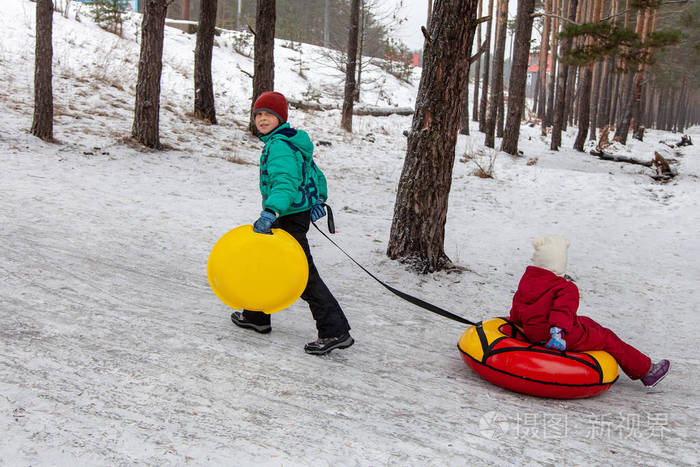 哥哥拉着妹妹在山上的油管雪橇在户外冬天白天冬季游戏和乐趣