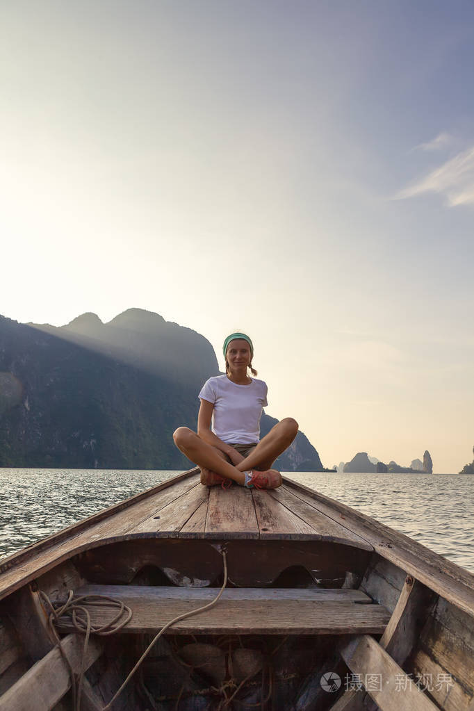 日出时坐在长尾船前面的年轻女子