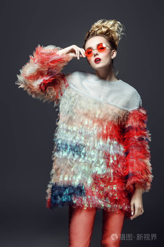 现代年轻女子穿着蓬松的衣服,在灰色的背景上摆姿势. 美容街时尚.