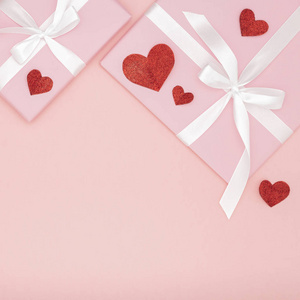 情人节理念构图 粉红色礼品盒, 白色丝带和小红心纸珊瑚背景。顶部视图。爱天概念平放置