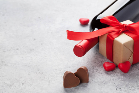 情人节贺卡上有酒瓶巧克力心和石头背景的礼品盒