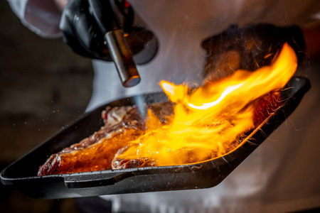 近景厨师烧烤排骨与烹饪燃烧器
