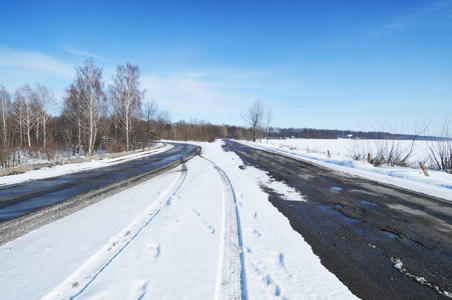 空旷的乡村道路和森林，冬天有雪和蓝天