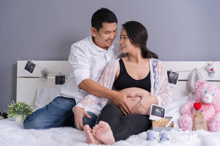 丈夫和他怀孕的妻子双手抱着心在床上