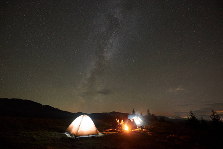 一组四人游客，男女在夜间篝火露营时休息
