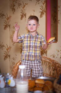 小男孩在桌子旁的厨房里吃馅饼。 在内部拍摄复古风格。