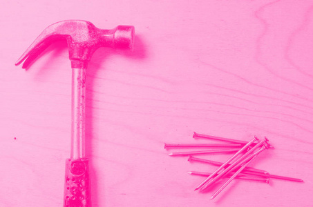 胶合板背景下的锤子和钉子. 平视. 粉色色调. 女权主义的概念.照片