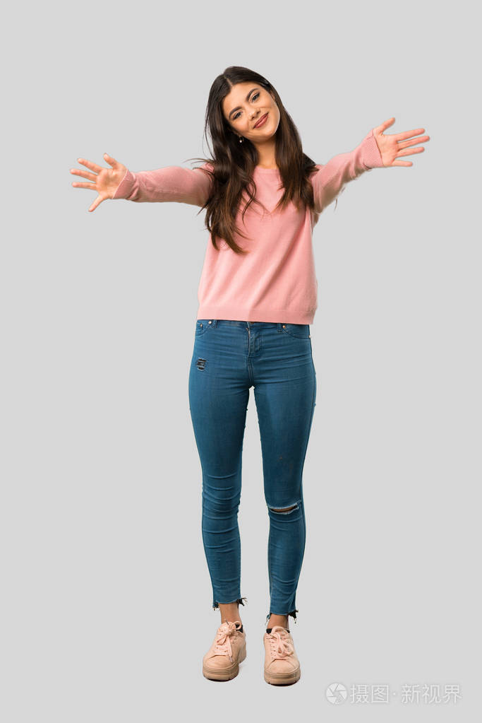 全身的青少年女孩粉红色的衬衫呈现和邀请与手在孤立的灰色背景