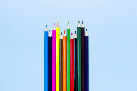 彩色铅笔在蓝色背景顶部视图平面与复制空间。 木制彩色铅笔，用于绘制创意物品，学校用品关闭。 回到学校的概念