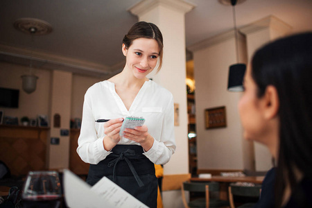 她写命令. 女服务员看着顾客微笑. 他们在餐馆里照片