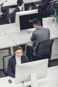 在开放式办公室使用台式电脑的男女商人的高视角