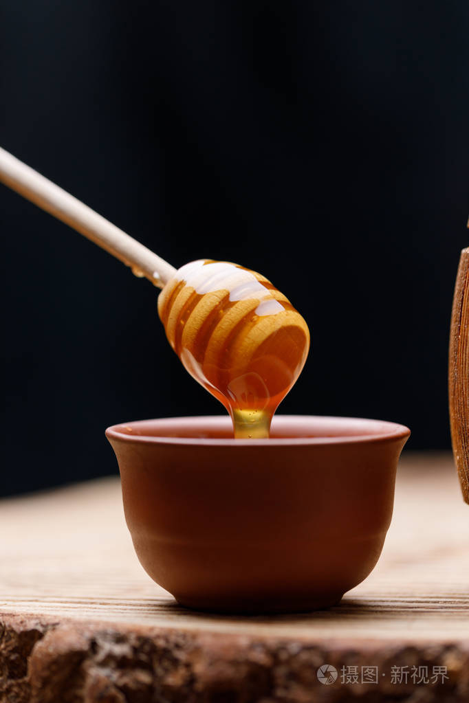蜂蜜勺子蘸着一碗芬芳的蜂蜜近点