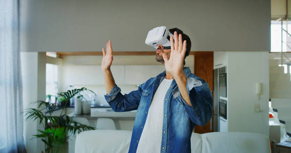客厅里用VR眼镜的帅哥肖像。 创新科技生活方式娱乐理念。