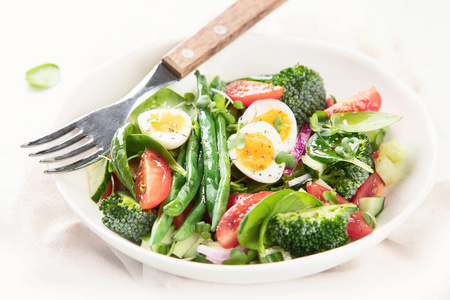 一碗新鲜蔬菜沙拉，鸡蛋，青豆，西兰花和西红柿。