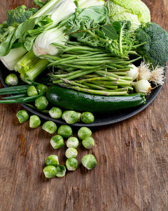 木制桌子上有新鲜的绿色蔬菜。