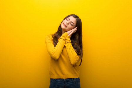 活力少女意思少女在充满活力的黄色背景下做睡眠手势,表情照片