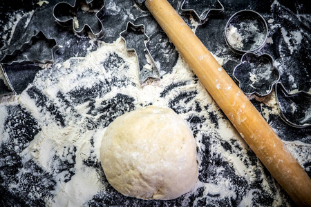 揉面团，擀面杖和饼干刀在一张铺着面粉的桌子上。