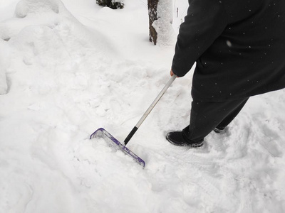 人们用铲子从小路上清除雪，冬天的雪天背景。 在大雪中，人们在车道上铲雪。 特写构图