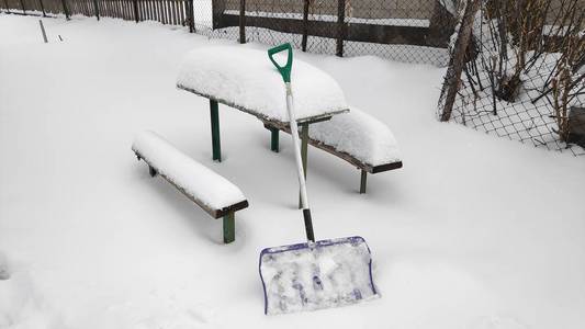 人们用铲子从小路上清除雪，冬天的雪天背景。 在大雪中，人们在车道上铲雪。 特写构图