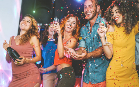 快乐的朋友在俱乐部喝香槟和跳舞，千禧一代代的年轻人在夜总会里快乐地庆祝夜生活娱乐和节日的概念