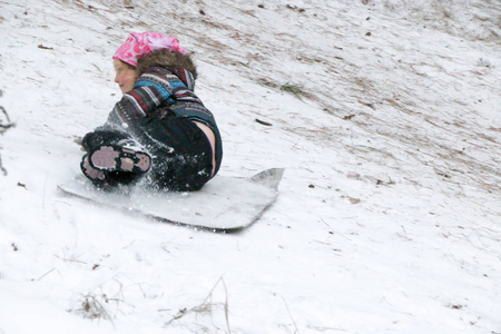 在冬天的松林乌克兰苏米地区，小女孩乘雪橇从山上滚下来