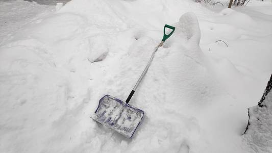 人们用铲子从小路上清除雪，冬天的雪天背景。 在大雪中，人们在车道上铲雪。 特写构图