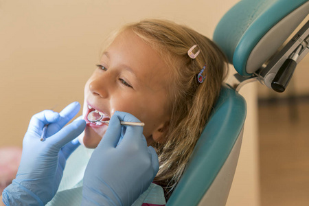 s . little girl sitting in a chair near a dentist after de