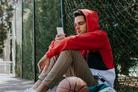 在篮球场上拿着手机的年轻人
