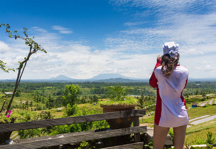 家庭度假的生活方式。年轻女子站在悬崖峭壁上的悬索桥边上。快乐的女孩在迷人的热带丛林景观。图卡德梅兰吉特是巴厘岛热门的旅游目的地
