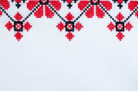 红黑棉线在白衬里手工刺绣.民族纹理的设计。十字绣图案工艺刺绣。背景与刺绣。几何民间装饰。