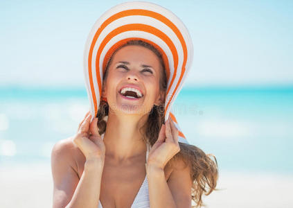海滩上戴帽子微笑的年轻女子画像