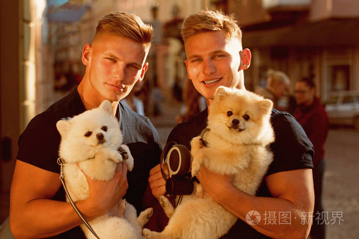 双胞胎男人抱着血统的狗.肌肉发达的人与狗宠物.