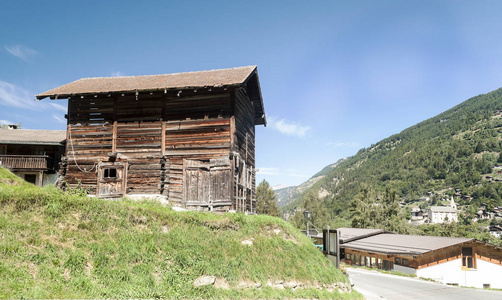 阳光明媚的一天，圣卢克山谷瑞士阿尔卑斯山草地上的木屋。